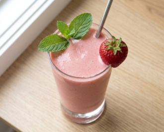 Vaso de agua de fresa cremosa y trozos de fruta