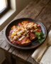 Plato típico mexicano con enchiladas mineras originales bañadas en salsa de chile guajillo, decoradas con papas, zanahorias, queso fresco y crema.