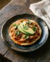 Plato típico mexicano con enchiladas mineras originales bañadas en salsa de chile guajillo, decoradas con papas, zanahorias, queso fresco y crema.